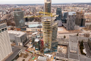 Şehrin insansız hava aracı fotoğrafçılığı ve bulutlu bahar günlerinde gökdelen inşaatı. Yüksek açı görünümü