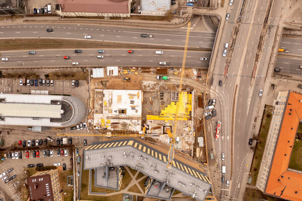 Drone photography of building construction site near a high traffic street during early spring cloudy day. Directly above
