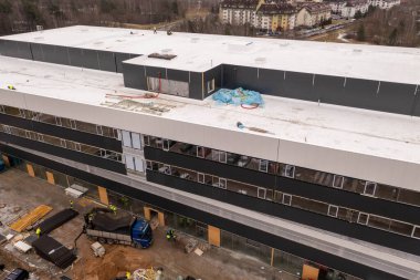 İnşaat alanının drone fotoğrafları ve inşaat işçilerinin inşaat işlerini bahar bulutlu günlerinde bitirmeleri. Yüksek açı görünümü.