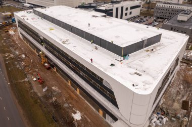 İnşaat alanının drone fotoğrafları ve inşaat işçilerinin inşaat işlerini bahar bulutlu günlerinde bitirmeleri. Yüksek açı görünümü.