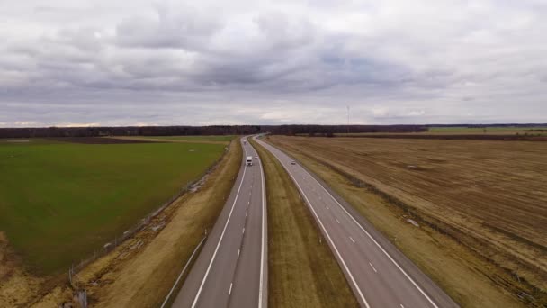 春の曇りの日に農地に囲まれた田舎の高速道路や交通のドローン映像 — ストック動画