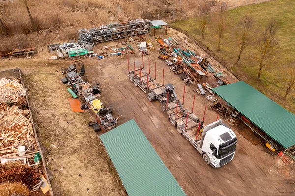 Drone photography of logging truck in a sawmill during cloudy spring day. High angle view.