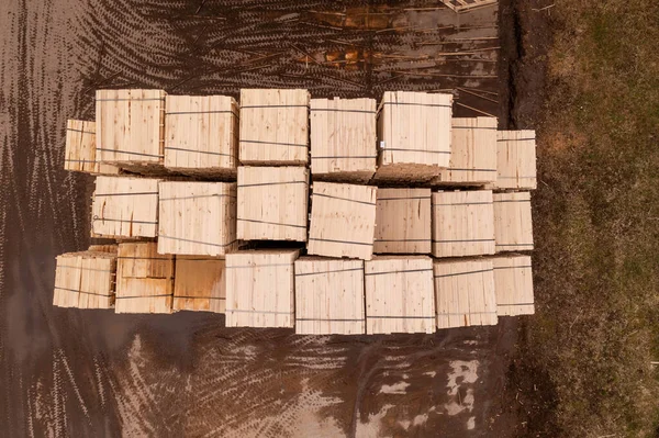 Drone footage piles of lumber in sawmill during summer day. Directly above