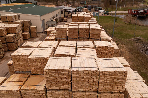 Drone footage piles of lumber in sawmill during summer day. High angle view