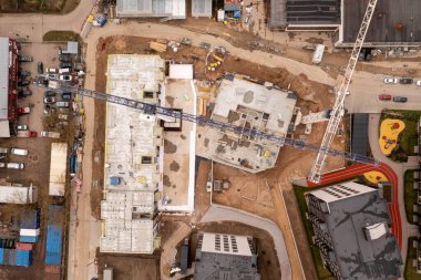 Güneşli bahar günlerinde diğer yapıların ortasında çok katlı apartman kompleksinin kentsel inşaat alanının insansız hava aracı fotoğrafları. Tam üstte