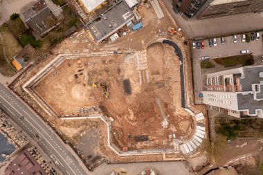 Güneşli bahar günlerinde diğer yapıların ortasındaki kentsel inşaat sahasının insansız hava aracı fotoğrafları. Tam üstte