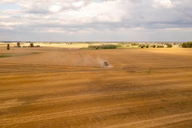 Güneşli yaz günlerinde traktörle arazi eken bir çiftçinin drone fotoğrafı.