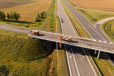 İnşaat işçilerinin, yaz boyunca bir köprüyü kontrol eden ve tamir eden vinçle drone fotoğrafları..