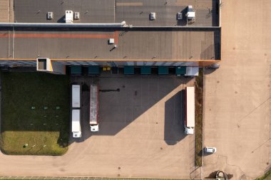 Güneşli bir günde lojistik depo ve kamyonların insansız hava aracı fotoğrafları. Tam üstte