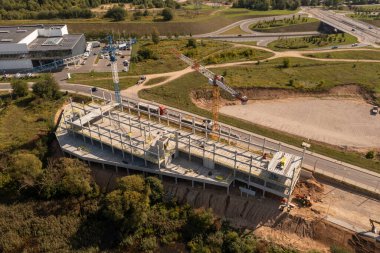 Sonbahar güneşli bir günde yeni inşaat şantiyesinin, vinçlerin ve inşaat işçilerinin insansız hava aracı fotoğrafları.