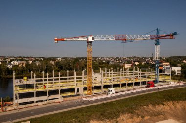 Sonbahar güneşli bir günde yeni inşaat şantiyesinin, vinçlerin ve inşaat işçilerinin insansız hava aracı fotoğrafları.