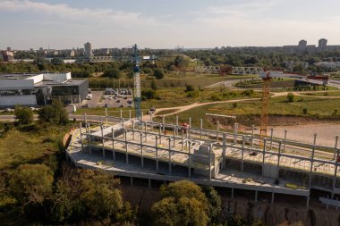 Sonbahar güneşli bir günde yeni inşaat şantiyesinin, vinçlerin ve inşaat işçilerinin insansız hava aracı fotoğrafları.