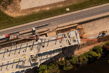 Sonbahar güneşli bir günde yeni inşaat şantiyesinin, vinçlerin ve inşaat işçilerinin insansız hava aracı fotoğrafları.
