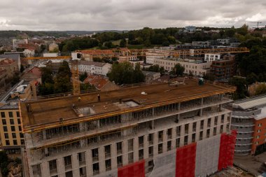 Bulutlu sonbahar gününde yeni inşaat alanı, vinç ve şehir manzarasının insansız hava aracı fotoğrafçılığı