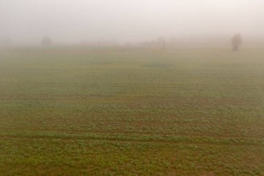 Sonbahar sabahı sisli ve bulutlu bir günde çayır ve tarım arazilerinin insansız hava aracı fotoğrafçılığı