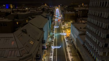 Karlı kış gecelerinde şehir merkezinde Noel süslemeleri olan bir caddenin insansız hava aracı fotoğrafı.