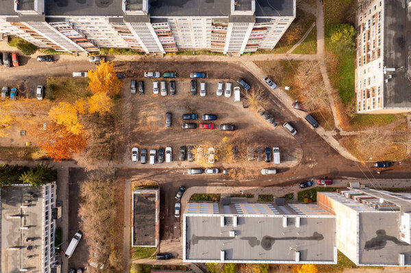Drone photography of multistory houses and parking place between them in a city during autumn sunny day