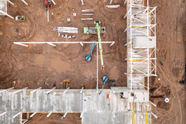 Sonbahar güneşli sabahları inşaat makineleri ve inşaat işçileri olan büyük ticari binaların inşaat alanlarının insansız hava aracı fotoğrafları.