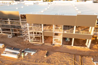 Sonbahar güneşli sabahları inşaat makineleri ve inşaat işçileri olan büyük ticari binaların inşaat alanlarının insansız hava aracı fotoğrafları.