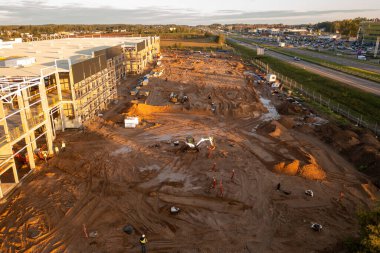 Sonbahar güneşli sabahları inşaat makineleri ve inşaat işçileri olan büyük ticari binaların inşaat alanlarının insansız hava aracı fotoğrafları.