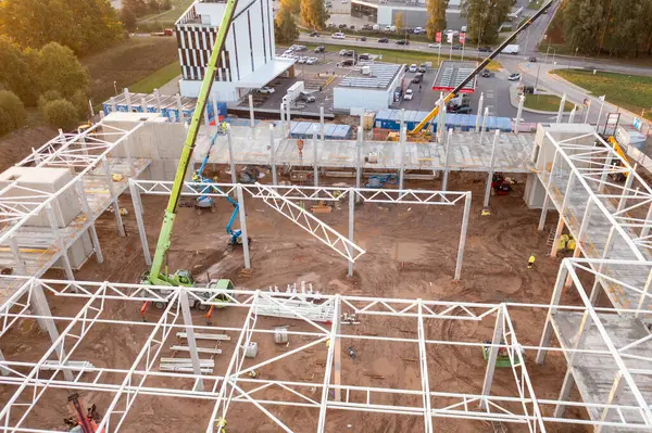 Sonbahar güneşli sabahları inşaat makineleri ve inşaat işçileri olan büyük ticari binaların inşaat alanlarının insansız hava aracı fotoğrafları.