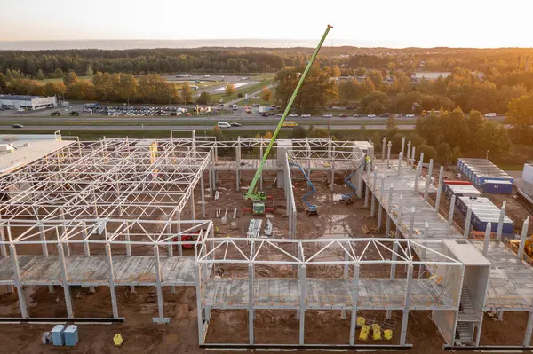 Sonbahar güneşli sabahları inşaat makineleri ve inşaat işçileri olan büyük ticari binaların inşaat alanlarının insansız hava aracı fotoğrafları.