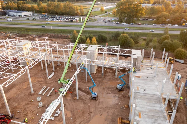 Sonbahar güneşli sabahları inşaat makineleri ve inşaat işçileri olan büyük ticari binaların inşaat alanlarının insansız hava aracı fotoğrafları.