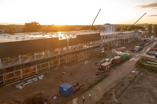 Sonbahar güneşli sabahları inşaat makineleri ve inşaat işçileri olan büyük ticari binaların inşaat alanlarının insansız hava aracı fotoğrafları.