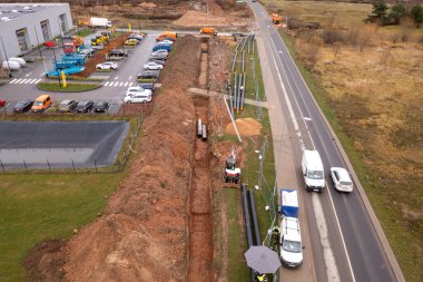 Kanalizasyon borusunun sonbahar bulutlu bir günde yol kenarındaki bir hendekte sürüklendiğini gösteren drone fotoğrafı.
