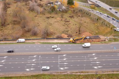 Kanalizasyon borusunun sonbahar bulutlu bir günde yol kenarındaki bir hendekte sürüklendiğini gösteren drone fotoğrafı.