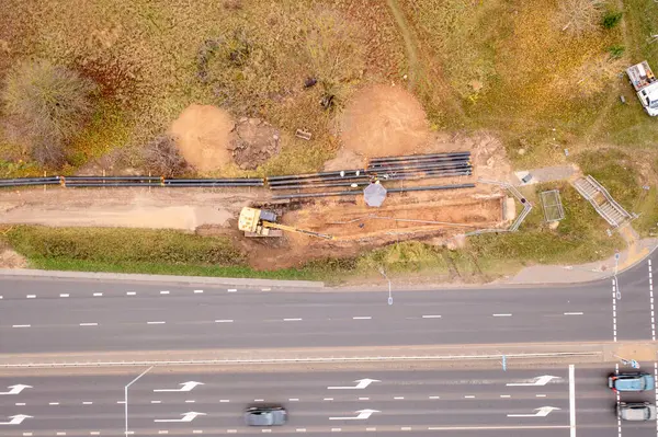 Kanalizasyon borusunun sonbahar bulutlu bir günde yol kenarındaki bir hendekte sürüklendiğini gösteren drone fotoğrafı.