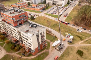 Sonbahar güneşli bir günde vinç çatıdan inşaat malzemelerini çıkartırken çekilen İHA fotoğrafı