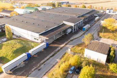 Sonbahar güneşli günlerinde park halindeki kamyonlarla büyük depo kompleksinin insansız hava aracı fotoğrafları.