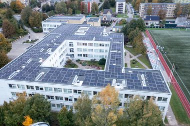 Sonbahar güneşli akşamları çatıda güneş panelleri olan okul binasının insansız hava aracı fotoğrafları.