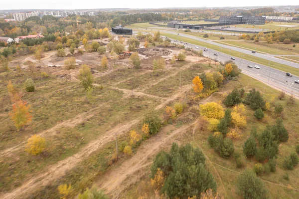 Drone photography of construction waste dumping site and machinery grinding it during autumn cloudy day