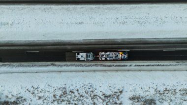 Kışın bulutlu bir sabahta otoyolda yanmış bir kamyonu çeken bir kamyonun drone fotoğrafı.