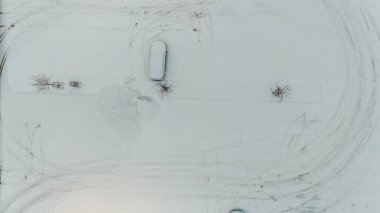 Boş bir otoparkın insansız hava aracı fotoğrafı ve kış bulutlu bir günde karla kaplı bir araba.