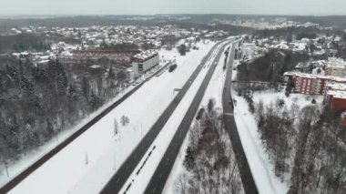 Evlerin drone görüntüleri, çoklu şerit otoyol ve kış tipi boyunca karla kaplı şehir.