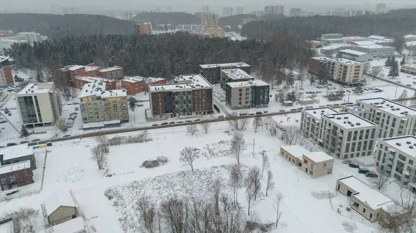 Drone photography of a city landscape, buildings, public parks covered in snow during winter cloudy day