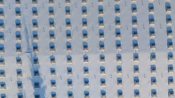 Drone photography of a large building rooftop with skylights covered by snow during winter sunny day