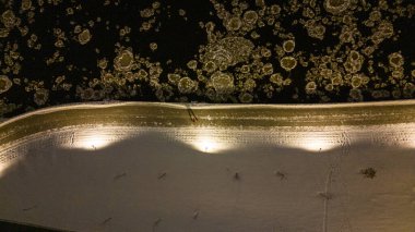 Nehrin yukarısındaki buzlu suyun drone fotoğrafları, yanındaki patika ve kış bulutlu gecelerde yürüyen insanlar.