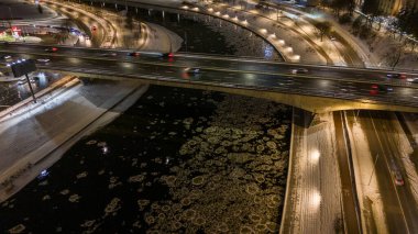 Buzlu nehrin, köprünün ve arabaların kış bulutlu gecelerinde sürüşünün insansız hava aracı fotoğrafları