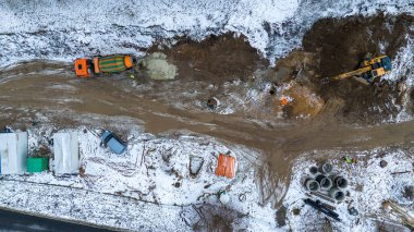 Kış bulutlu bir günde karla kaplı bir şehirdeki küçük yapıların insansız hava aracı fotoğrafları.