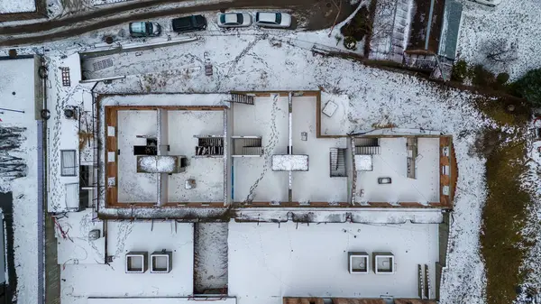 Drone photography of unfinished and abandoned building in a city covered by snow during winter cloudy day
