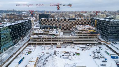 Bulutlu kış gününde karla kaplı bir şehirde binalarla çevrili yapıların insansız hava aracı fotoğrafları.