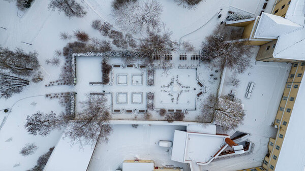 Drone photography of small public park with hedge covered by snow in a city during winter cloudy day
