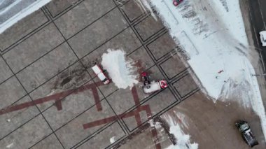 Kamu meydanındaki karları temizleyen traktörün kış bulutlu bir günde drone görüntüleri.