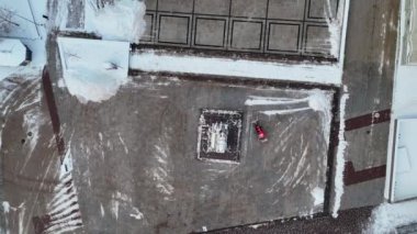 Kamu meydanındaki karları temizleyen traktörün kış bulutlu bir günde drone görüntüleri.