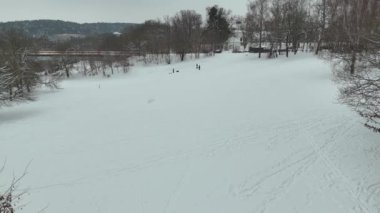 Bulutlu kış gününde parkta karla oynayan çocukların İHA görüntüleri