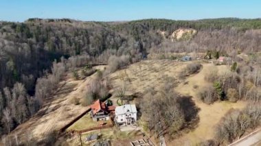 Kırsal arazinin insansız hava aracı görüntüleri ve güneşli bahar günlerinde nehir kenarında birkaç ev.